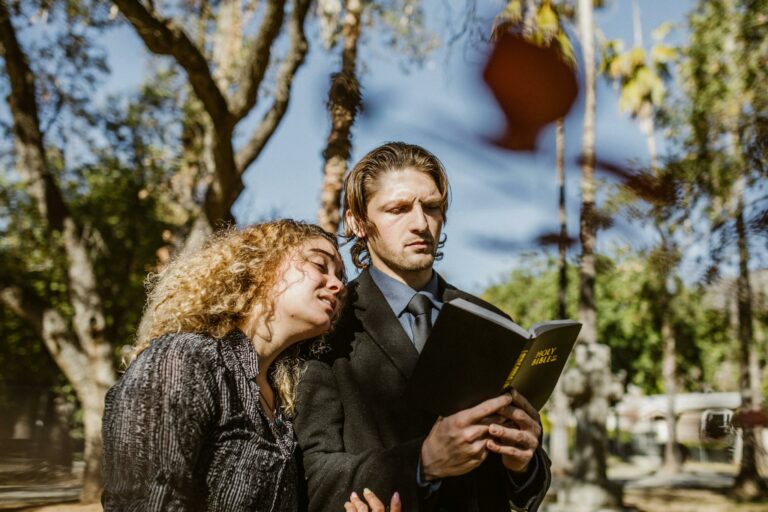 A couple standing in a cemetery, reading from the Bible, signifies faith and companionship.